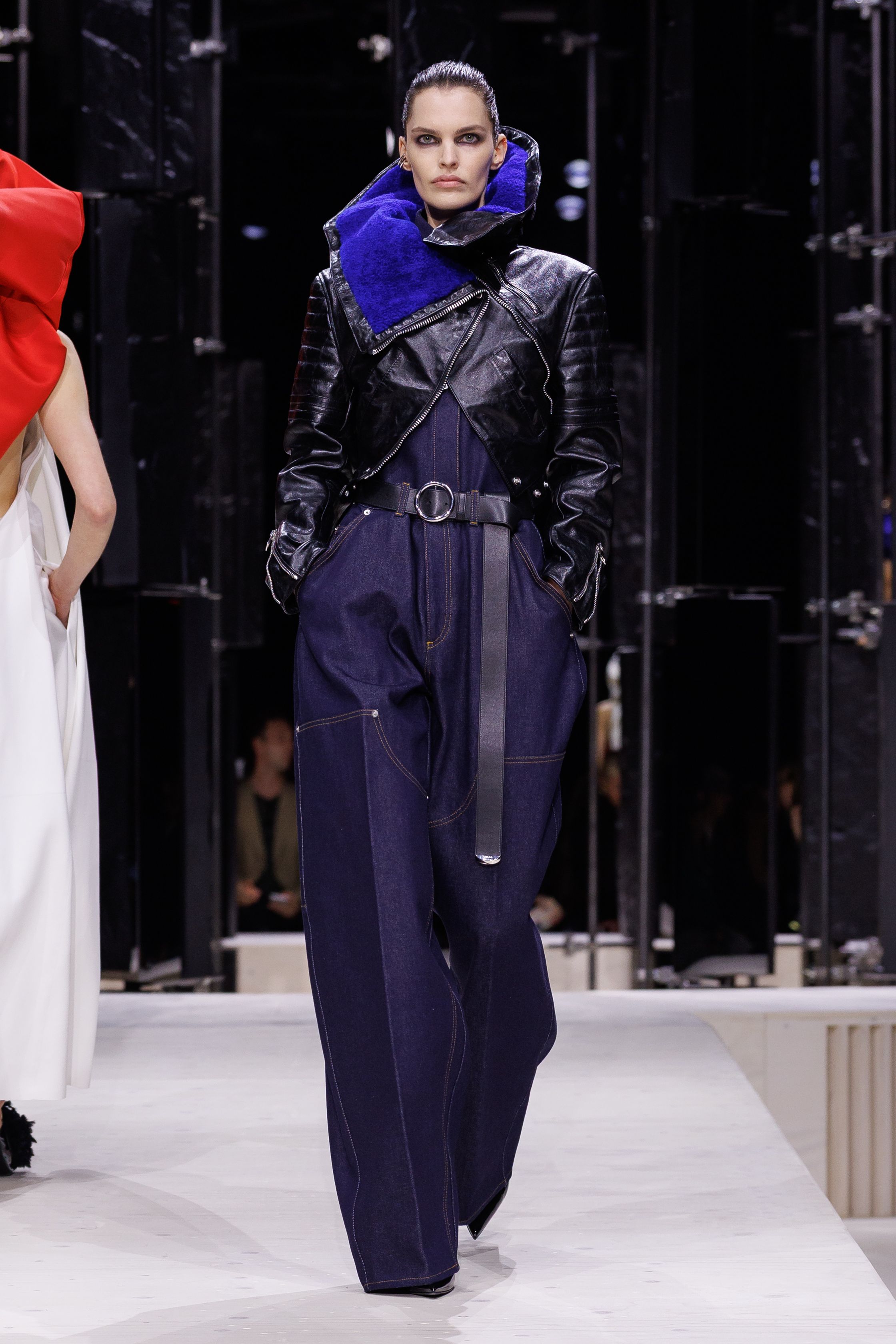 Givenchy 2026秋冬在现代建筑空间中呈现一场充满戏剧性的时装叙事：雕塑式西装、亮色斗篷、结构礼服与夸张装饰共同构建品牌标志性的高级时装气质。蓝色、红色与黄色的高饱和色彩与黑白经典形成鲜明对比，服装通过立体剪裁与夸张廓形展现出强烈视觉张力。整场系列在优雅与戏剧之间取得平衡，展现现代高级时装的力量-顽石频道趋势研究